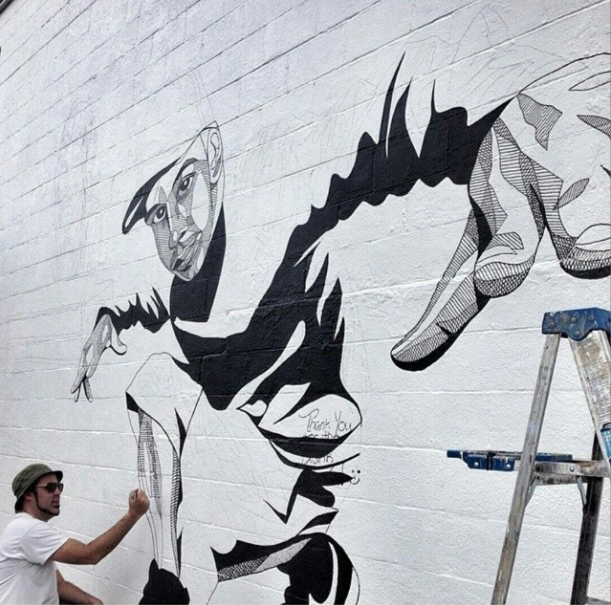 ANDREW SPEAR WORKING ON A MILLS 50 MURAL