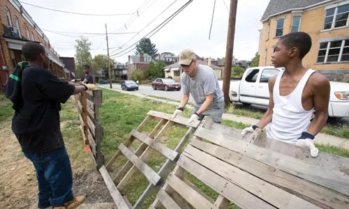 Andrew Butcher of GTECH (center) helps neighborhood kids build a fence. GTECH, a nonprofit, is helping plant biofuel crops in East Liberty.