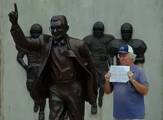 Bernie McCue protests next to the Joe Paterno statue in Happy Valley