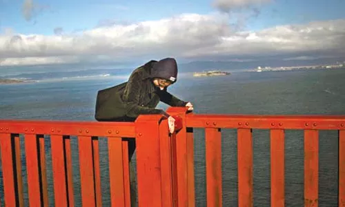 On the edge: As captured by tourist Richard Waters, a would-be jumper scales the railing on the Golden Gate Bridge.