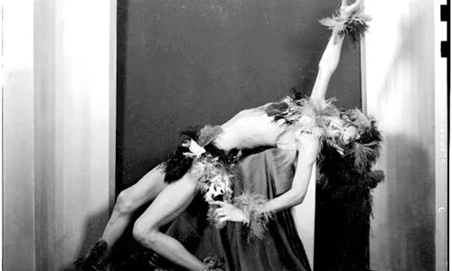 "Portrait of male dancer in exotic feathered costume, in reclining pose against curtain, in Harris Studio, c. 1940-1945," by Teenie Harris.