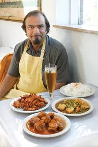 Syed Chand, with traditional Pakistani dishes chicken tikka masala, green peas and potatoes, and vegetable pakora - HEATHER MULL
