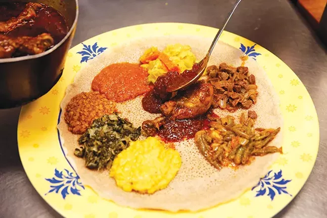 Owner Seifu Haileyesus prepares a sampler of various meats and vegetables. - CP PHOTO: JARED WICKERHAM