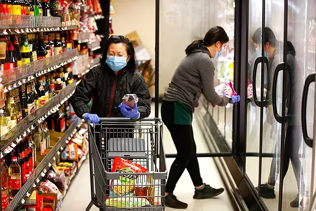 Employees of Panda Supermarket on Forbes Avenue in Squirrel Hill fulfill orders for customers inside the store on Thu., April 2, 2020. - CP PHOTO: JARED WICKERHAM