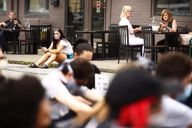 Diners eating on the patio at Mercurio's look on as protesters stage a sit-in along Walnut Street in the Shadyside neighborhood. - CP PHOTO: JARED WICKERHAM