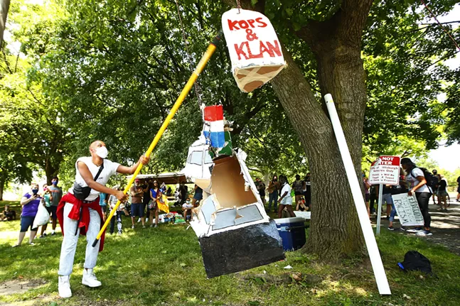 Christian Carter smashes a police car pinata at the start of the Juneteenth celebration in Mellon Park. - CP PHOTO: JARED WICKERHAM