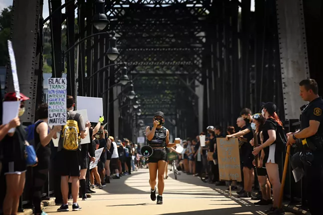 Jalina McClarin leads chants as she marches down the Hot Metal Bridge walkway amidst a line of both protesters and Pittsburgh police officers. - CP PHOTO: JARED WICKERHAM