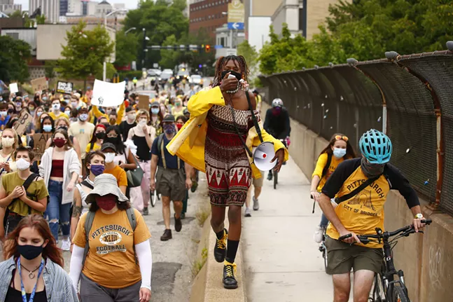 Protesters march through Oakland past the campus of Carnegie Mellon University. - CP PHOTO: JARED WICKERHAM