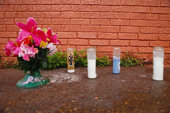 Flowers and candles left in front of a painted-over Ramir Talley mural in Wilkinsburg - CP PHOTO: JARED WICKERHAM