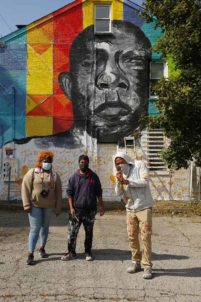 Adrie Rose, program assistant for Carlow University Social Justice Institutes, Zim Syed, lead artist, and Kyle Holbrook, executive artist with MLK Mural Project, pose for a portrait in front of the John Lewis mural in Uptown. - CP PHOTO: JARED WICKERHAM