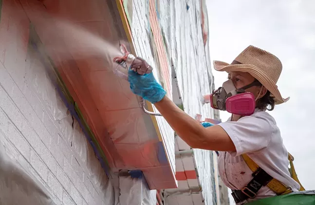Artist Ann Lewis works on her To Be Human mural at the Duolingo offices in Pittsburgh - PHOTO BY RENEE ROSENSTEEL