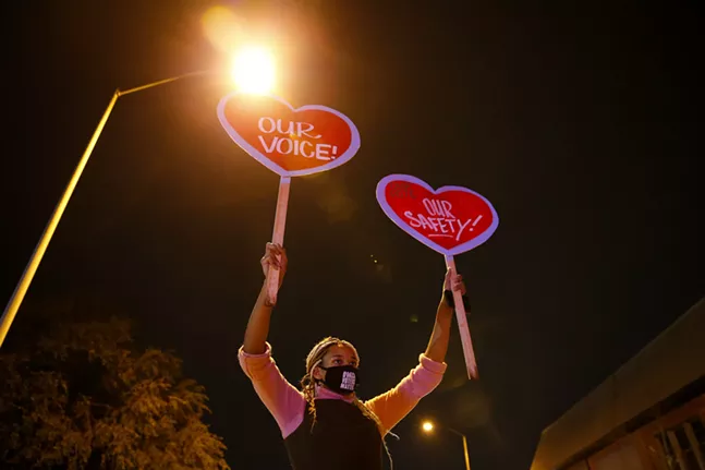 Chrissy Carter holds up signs as marchers chant in front of the Allegheny Elections warehouse. - CP PHOTO: JARED WICKERHAM