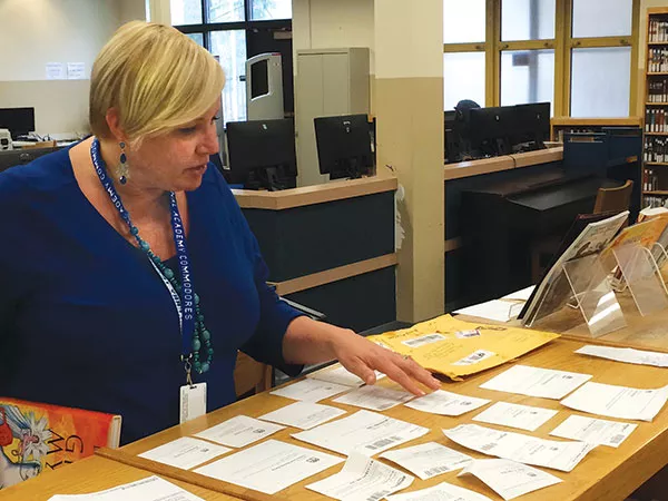 Librarian Sheila May-Stein reviews the dozens of Amazon gift notices she received with donated books. - PHOTO BY ALLAN SMITH