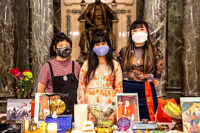 Organizers Anny Chen, Lena Chen, and Caroline Yoo stand behind an altar where people brought offers for victims of the Atlanta shooting during an event in support of Asian American and Pacific Island women and sex workers at the Carnegie Museum of Art on April 1. - CP PHOTO: KAYCEE ORWIG