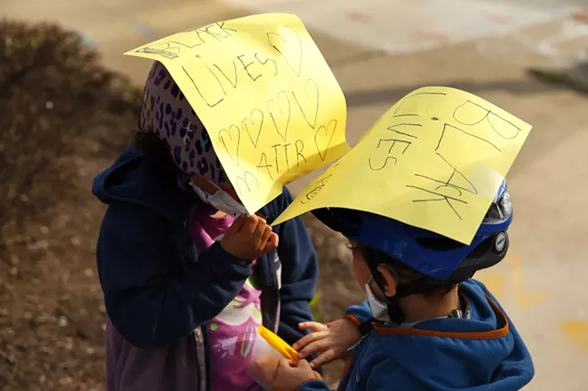 Sylvie, 6, and Eli, 4, share snacks while wearing signs on their bicycle helmets before protesters march. - CP PHOTO: JARED WICKERHAM