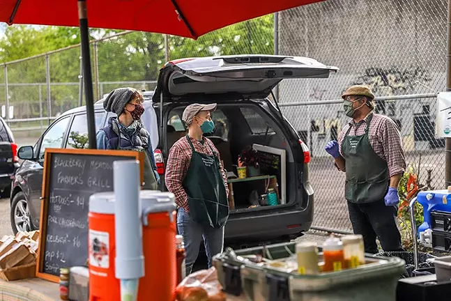 Workers at Bluberry Meadow Farmer’s Grill talk behind their booth at a farmers market in East Liberty on May 10 - CP HHOTO: KAYCEE ORWIG
