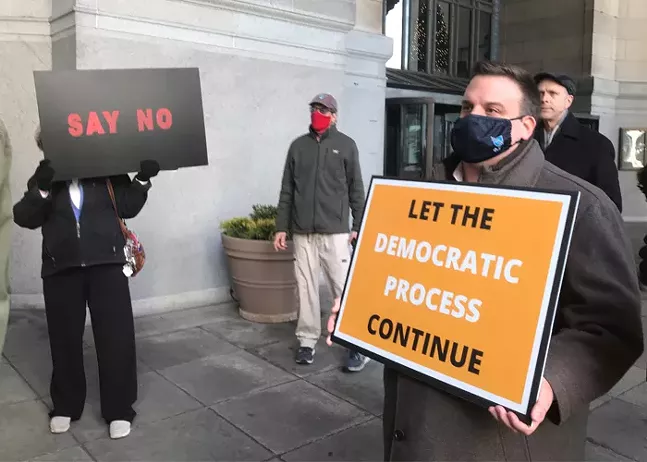 A supporter and an opponent of the Wilkinsburg-Pittsburgh merger listen during a rally in Downtown Pittsburgh on Jan. 5. - CP PHOTO: JORDANA ROSENFELD