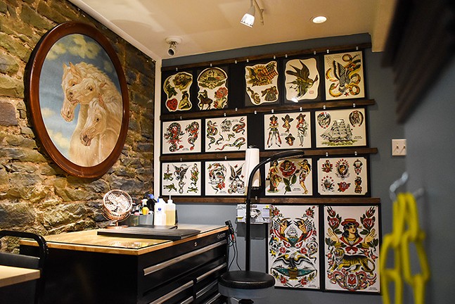 A bunch of images of tattoo designs hung in a display on a wall