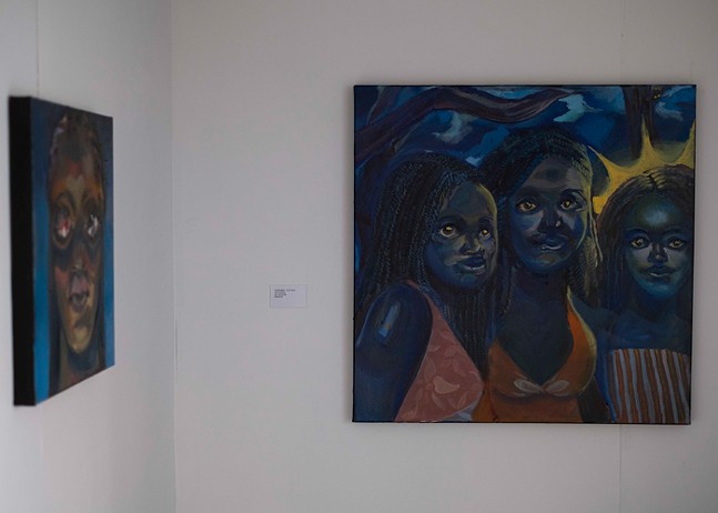 A blue painting depicting three smiling Black women hangs as part of the exhibition Dream of a Black Planet.