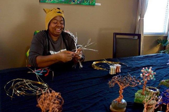 Artist Lisa Tabb smiles in a Winnie the Pooh hat as she makes her spinning trees artwork at Art JAM