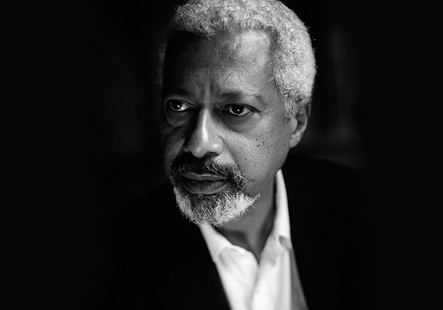 A Black man with gray hair and a salt-and-pepper goatee wears a suit and stares off to the side in this black-and-white photo
