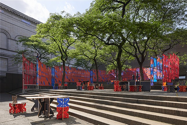 Scaffolding in an outdoor area covered in red and blue fabric.