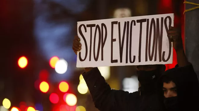 Lou, a Pittsburgh resident facing eviction, holds up a sign as traffic passes by along Grant Street during a rally put on by the Pittsburgh chapter of the United Neighborhood Defense Movement outside of the City-County Building.