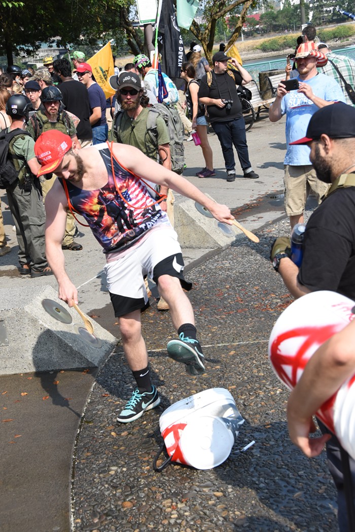 A right winger stomps on a bucket that was used by a protester as a drum