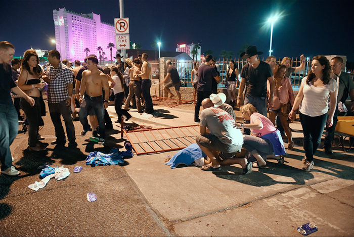 People tend to the wounded outside the Route 91 Harvest Country music festival grounds after an apparent shooting on October 1, 2017 in Las Vegas, Nevada. There are reports of an active shooter around the Mandalay Bay Resort and Casino.