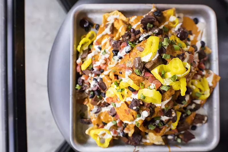 Burnt-end nachos include wonton chips, avocado crema, cheese sauce, kalamata olives, banana peppers and bean pico. - MABEL SUEN