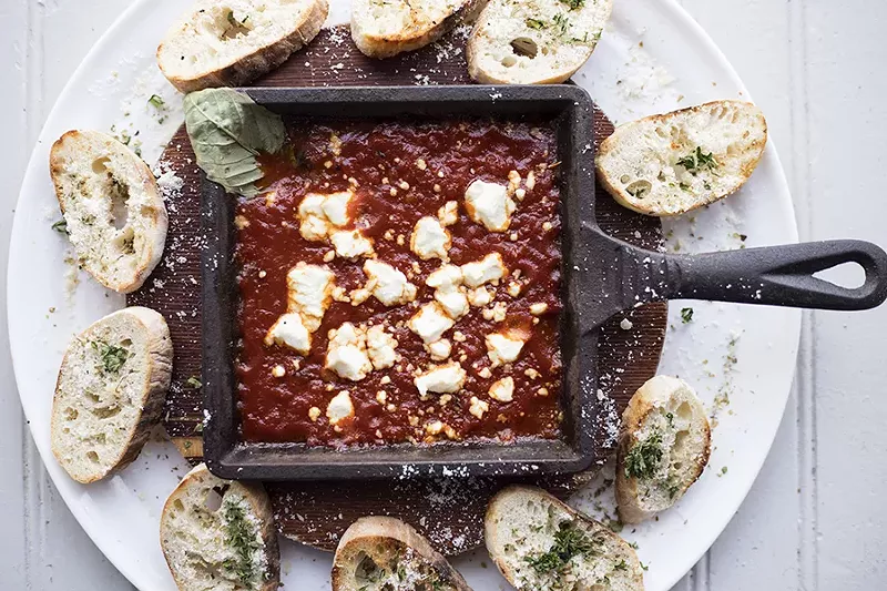 A baked goat cheese dip is served with bread for dipping. - MABEL SUEN