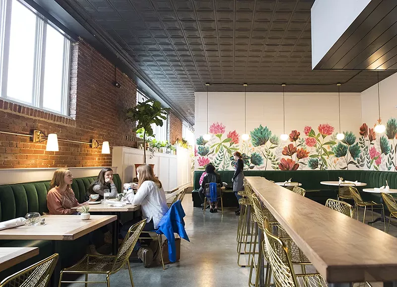 A vibrant floral mural beckons from the back wall, while green velvet banquettes line the walls. - MABEL SUEN