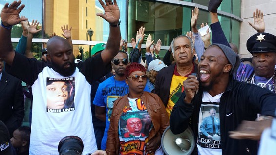 Michael Brown Sr. (L) gives the "Hands Up, Don't Shoot" sign during a protest with Lesley McSpadden, Michael Brown's mother, and Pastor Carlton Lee. - JESSICA LUSSENHOP