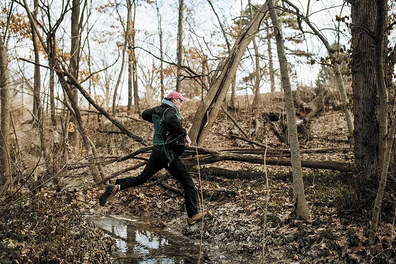Rob Connoley leaps over a stream during a recent foraging trip to Forest Park. - VIRGINIA HAROLD