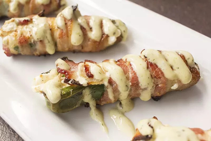 Bacon-wrapped stuffed jalapenos are filled with cream cheese, baked and drizzled with jalapeno ranch. - PHOTO BY MABEL SUEN