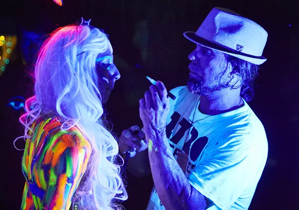 Weaver adds a touch of blue paint to a model's face during an installation showcase at last month's Cosmic Reunion festival. - PHOTO BY STEVE TRUESDELL