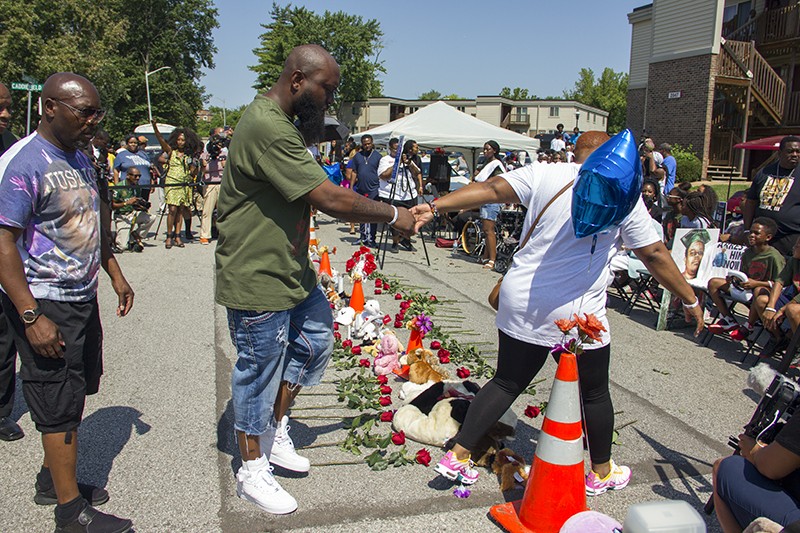 Cal Brown holds the hand of Michael Brown Sr. at their son's memorial on Canfield Drive. - DANNY WICENTOWSKI