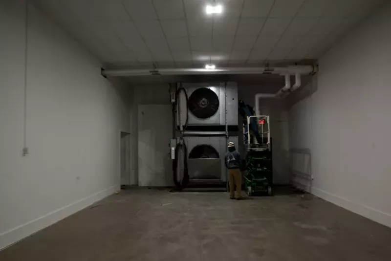 Workers tinker with fans inside the Dignity Transfer Center. - TRENTON ALMGREN-DAVIS