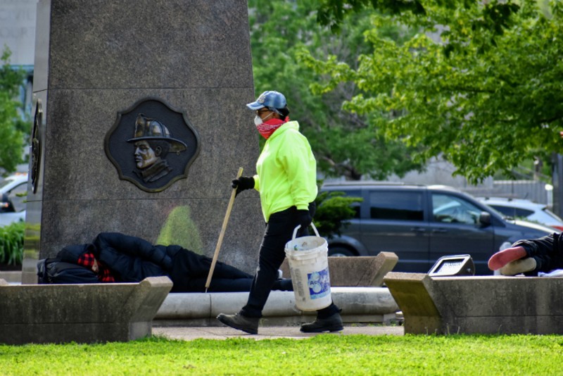 A worker picks up trash after the city removed two tent camps from downtown parks. - DOYLE MURPHY