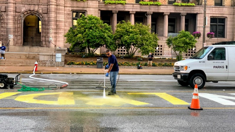A city worker power washes the LYDA RESIGN painted sign from Tucker Boulevard. - DOYLE MURPHY