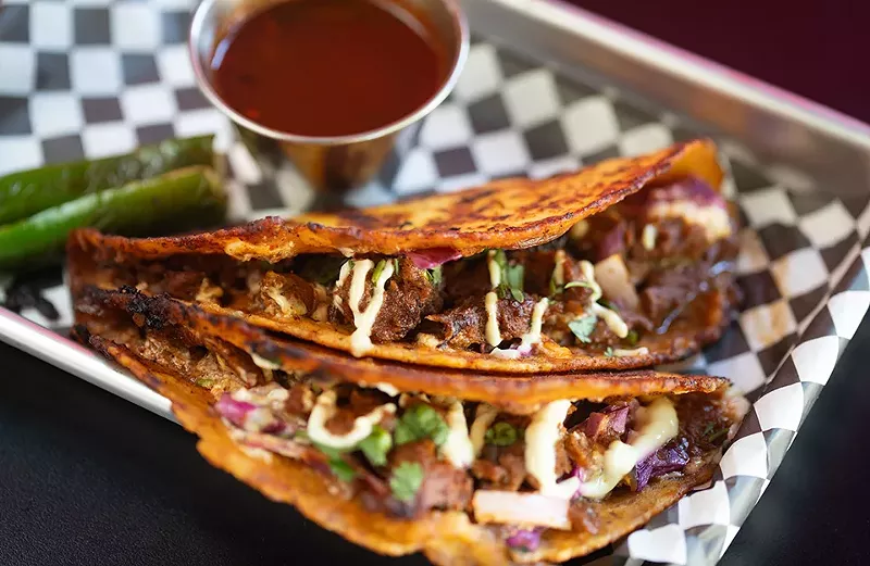 Birria tacos with housemade seitan marinated in vegan consomme, topped with sour cream, red cabbage, diced onions, cilantro and grilled jalapeños in corn tortillas. - MABEL SUEN