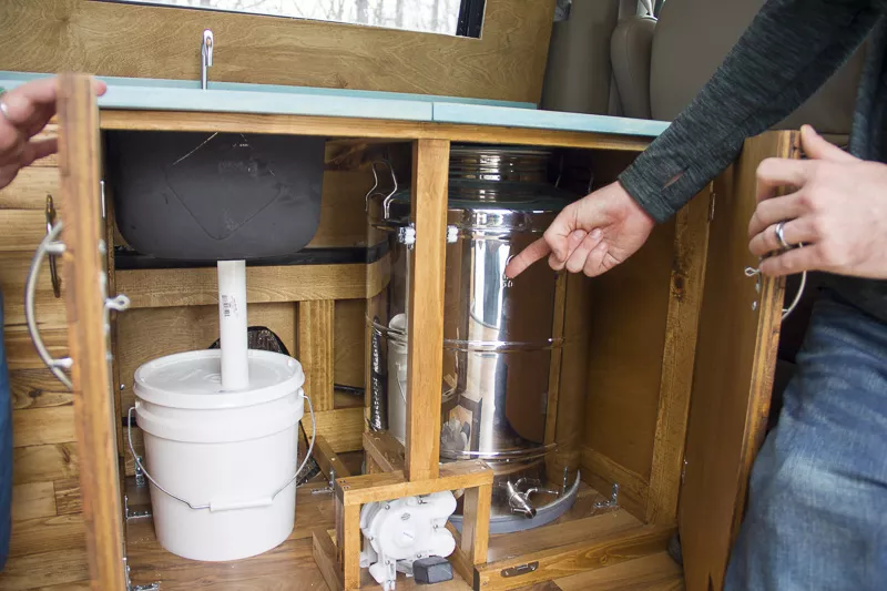 The Serbells show off their kitchenette, which includes a water tank, drain and storage. - PHOTO BY ALLISON BABKA
