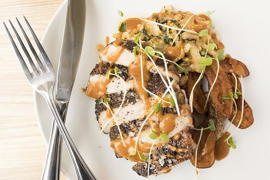 Coffee-crusted pork sits atop sauteed Asian greens, roasted potatoes and Thai curry. - MABEL SUEN
