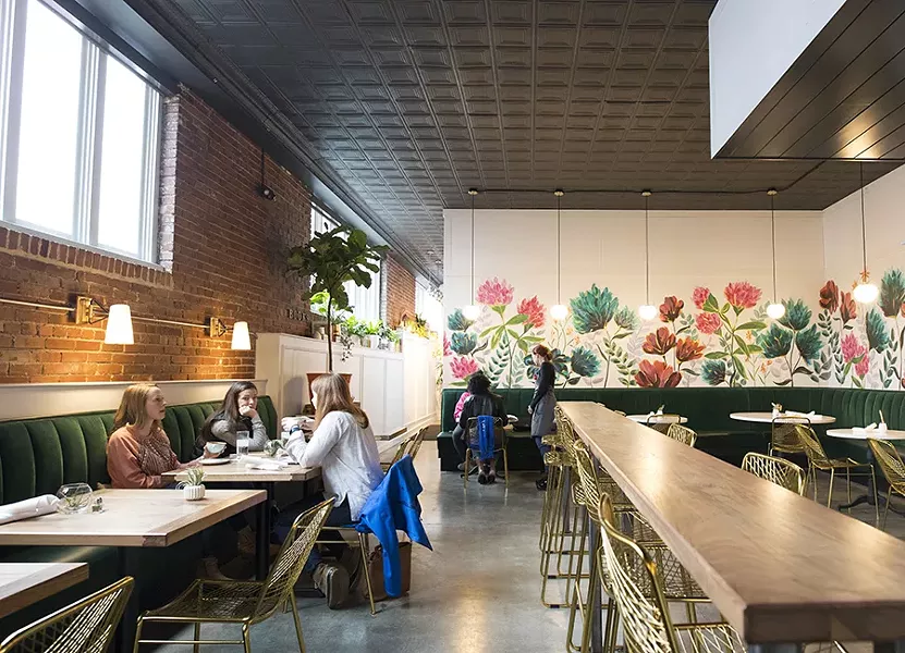 A vibrant floral mural beckons from the back wall, while green velvet banquettes line the walls. - MABEL SUEN