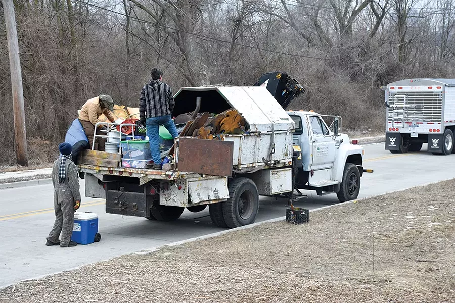 Along with two assistants, Phil Berwick (right), the artist behind the Merferd character, moves a resident's belongings into Berwick's tree-trimming truck. - DOYLE MURPHY