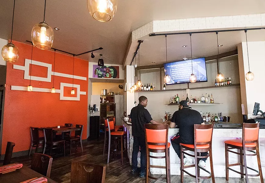 The dining room has been painted cream, save for one orange-red accent wall that matches the leather on the barstools and napkins. - MABEL SUEN