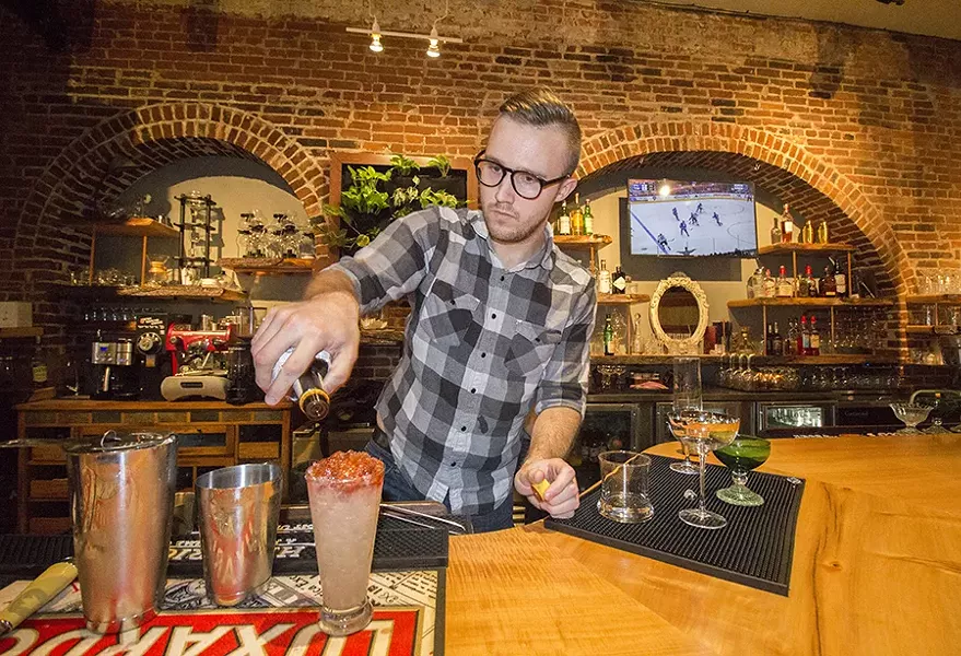 Bartender Tai Nalewajkó mixes drinks behind the bar. - PHOTO BY MABEL SUEN