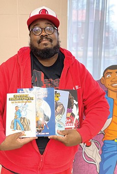 David Gorden poses with a selection of comics he's released to date.