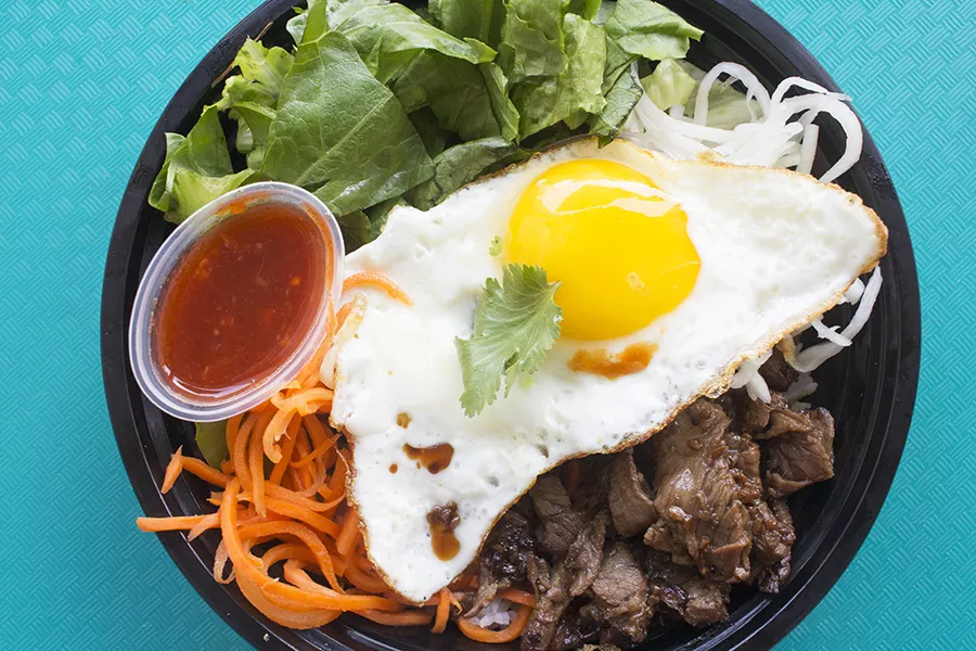The boneless beef short rib rice bowl is served with with jasmine rice, romaine, sweet pickled carrots, pickled daikon, a fried egg and chili sauce. - PHOTO BY MABEL SUEN