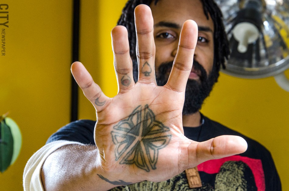 Adrien Moses Clark, a tattoo artist with Love Hate Tattoo, says the Flower City logo is a popular choice. He has one on his palm. - PHOTO BY MARK CHAMBERLIN